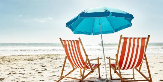 Liegestühle mit Sonnenschirm am Strand