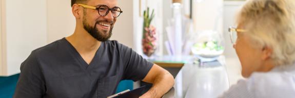 Arzthelfer und Patientn unterhalten sich