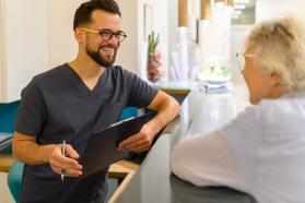 Arzthelfer und Patientn unterhalten sich